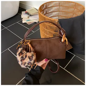 Detail of a dark brown cylinder bag with gold hardware and a leopard print heart charm