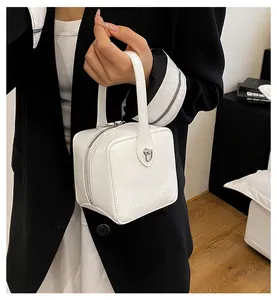 Close-up of white glossy box bag with embossed MAUDAI BEAR logo and metal zipper detail