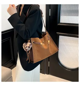 Detalle de bolso Kelly de ante marrón con cierre dorado y colgante de corazón de leopardo