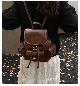 Detail view of a vintage dark brown leather backpack with silver buckles and side pockets