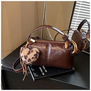 Close-up of vintage brown pillow bag featuring glossy finish and leopard heart charm