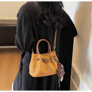 Detalle del bolso saco de ante naranja con correas de cuero y un pañuelo de seda a cuadros