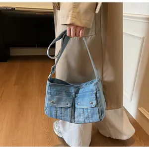 Detail shot of blue denim shoulder bag with metal buckle pockets and adjustable strap