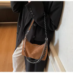 Dettaglio di una borsa a mezzaluna marrone con tre tracolle intercambiabili diverse
