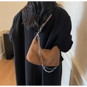 Dettaglio della borsa hobo in pelle opaca marrone con catena in metallo e tracolla