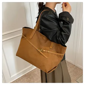 Close-up of caramel suede tote bag with decorative strap and golden metal buckle