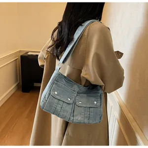 Detail of vintage blue denim shoulder bag with double front pockets and metal buttons
