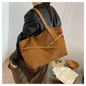 Detail of caramel suede tote bag featuring polished leather straps and gold buckle