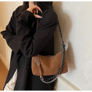 Dettaglio borsa in pelle opaca caramello con corda intrecciata bianca e nera e catena argento