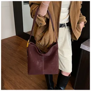 Detailaufnahme der burgunderroten Wildledertasche mit Kontrastnähten und goldener Schnalle