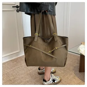 Detail view of large brown suede tote bag with decorative straps and golden metal buckles