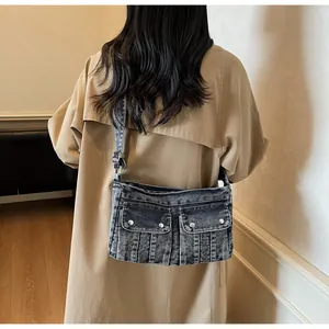 Detail of vintage denim shoulder bag with dual front pockets and silver buckle accents