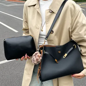Conjunto de bolso bandolera negro con cierre dorado y colgante de felpa elegante