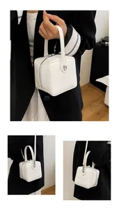 Detail of white square box bag with glossy finish and logo embossed on top handle