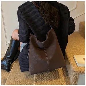Detailansicht der dunkelbraunen Wildledertasche mit weißen Kontrastnähten und weicher Textur