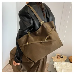 Detail of vintage brown suede tote bag featuring adjustable leather straps and gold buckle