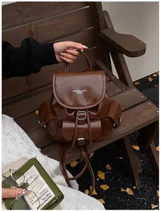 Detail of dark brown vintage faux leather backpack with buckle straps and drawstring on a bench
