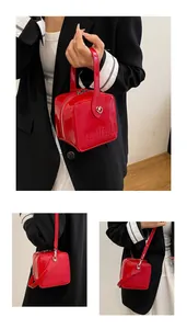 Detail of red patent leather square handbag with embossed text and heart zipper pull