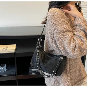 Dettaglio della borsa a mezzaluna nera opaca con tracolla a catena metallica e pelle nera