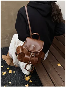 Close-up of vintage brown leather backpack with silver ginkgo leaves in autumn setting