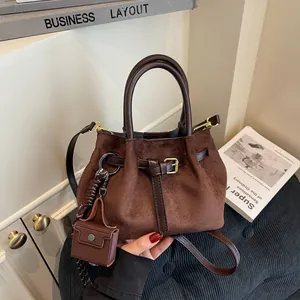 Bolso cubo retro de ante marrón con asas de cuero y un pequeño colgante de monedero