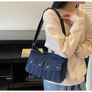 Detailed close-up of a vintage dark blue denim shoulder bag with dual front pockets