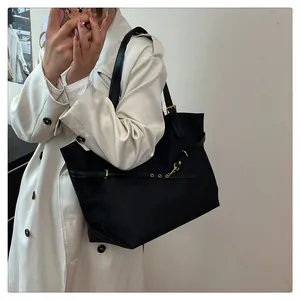 Close-up of black tote bag featuring premium texture and gold buckle detail on handle