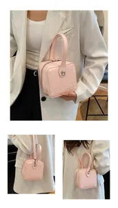 Detail of pink patent leather box bag featuring embossed logo and glossy metallic hardware