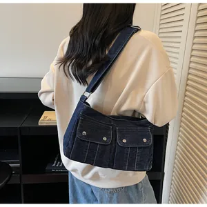 Detail of vintage blue denim shoulder bag featuring front pockets with metal buckles