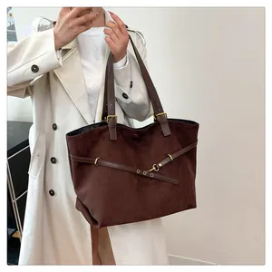Detail of dark brown suede tote bag with metal buckle and slender shoulder straps