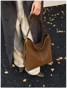 Details der braunen Wildleder-Beuteltasche mit Kontrastnähten und goldenem Vorhängeschloss