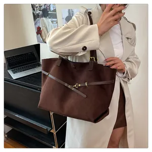 Detail of dark brown faux suede tote bag featuring a gold buckle and adjustable strap