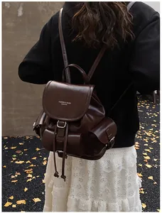 Detail of dark brown vintage faux leather backpack featuring flap cover and drawstrings