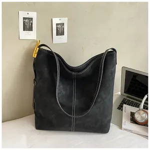 Detail einer schwarzen Wildleder-Hobo-Tasche mit stilvollen weißen Kontrastnähten im Alltag