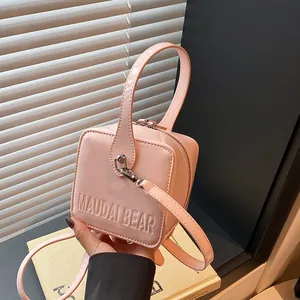 Detail of a pink glossy square bag with MAUDAI BEAR embossing and metal zipper