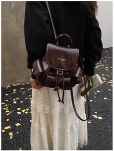 Detail of dark brown glossy leather backpack with silver buckles and drawstring closure