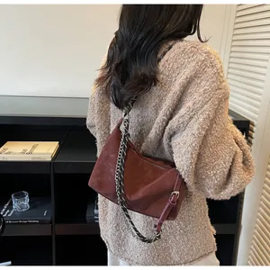 Dettaglio borsa a mezzaluna in pelle smerigliata bordeaux con catena e tracolla