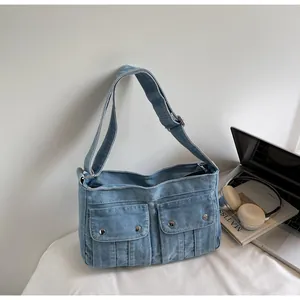 Detailed close-up of light blue denim shoulder bag with front pockets and silver hardware