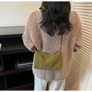 Dettaglio della borsa a mezzaluna verde oliva con texture opaca sulla spalla della modella