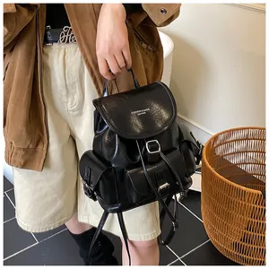 Detail of a vintage black leather backpack showing multiple pockets and buckle closures