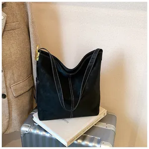 Detail der schwarzen Wildleder-Hobo-Tasche mit weißen Kontrastnähten und goldenen Beschlägen