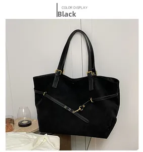 Detail of black suede tote bag with golden metal buckles and adjustable leather straps