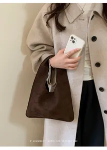 Detalle del bolso tote de ante marrón oscuro minimalista con abrigo de lana crema