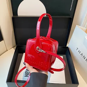 Detail of red patent leather square bag with MAUDAI BEAR embossed text in luxury setting
