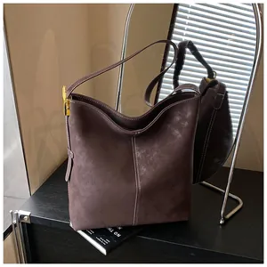 Detailansicht der dunkelbraunen Wildleder-Beuteltasche mit weißen Nähten und Gold-Hardware