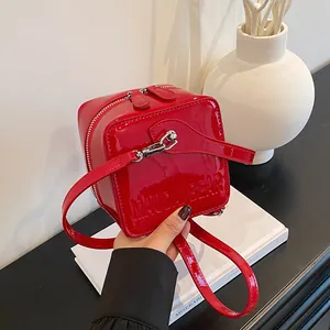 Detail of red patent leather square box bag featuring Maudai Bear embossed lettering