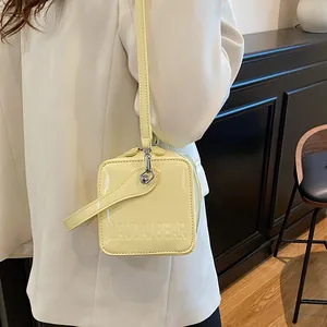 Close-up of a small square box bag in yellow patent leather with MAUDAI BEAR embossed text