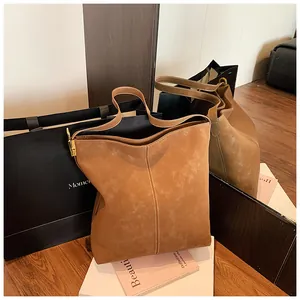 Details einer braunen Wildleder-Beuteltasche mit Kontrastnähten und goldener Hardware