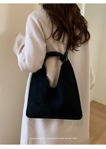 Detalle de bolso tote de ante negro con asa anudada y diseño de estilo retro y minimalista