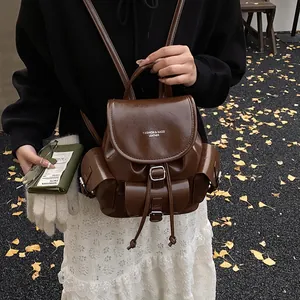 Vintage dark brown leather backpack with front pocket shown in an autumn park setting
